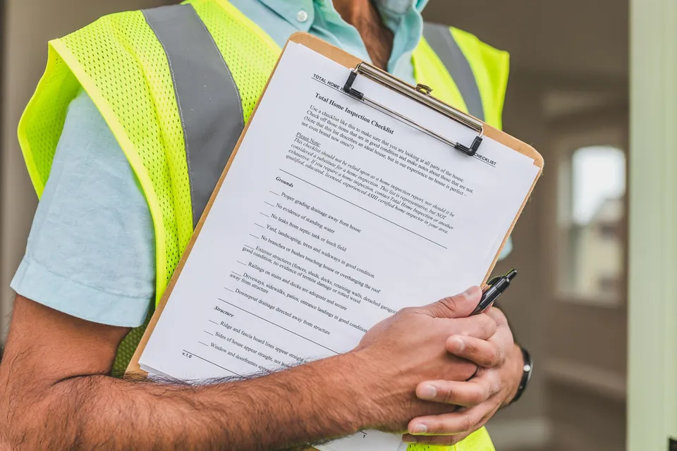 Persona con chaleco reflectante sosteniendo una lista de verificación en una carpeta