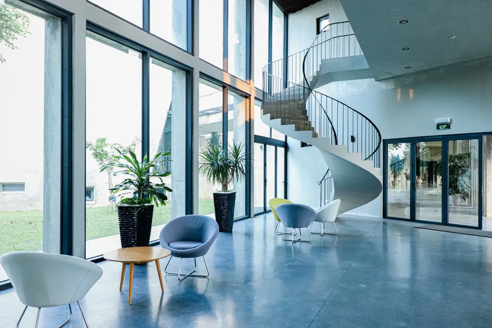 Lobby de un edificio de oficinas con ventanales, escalera de caracol y sillones