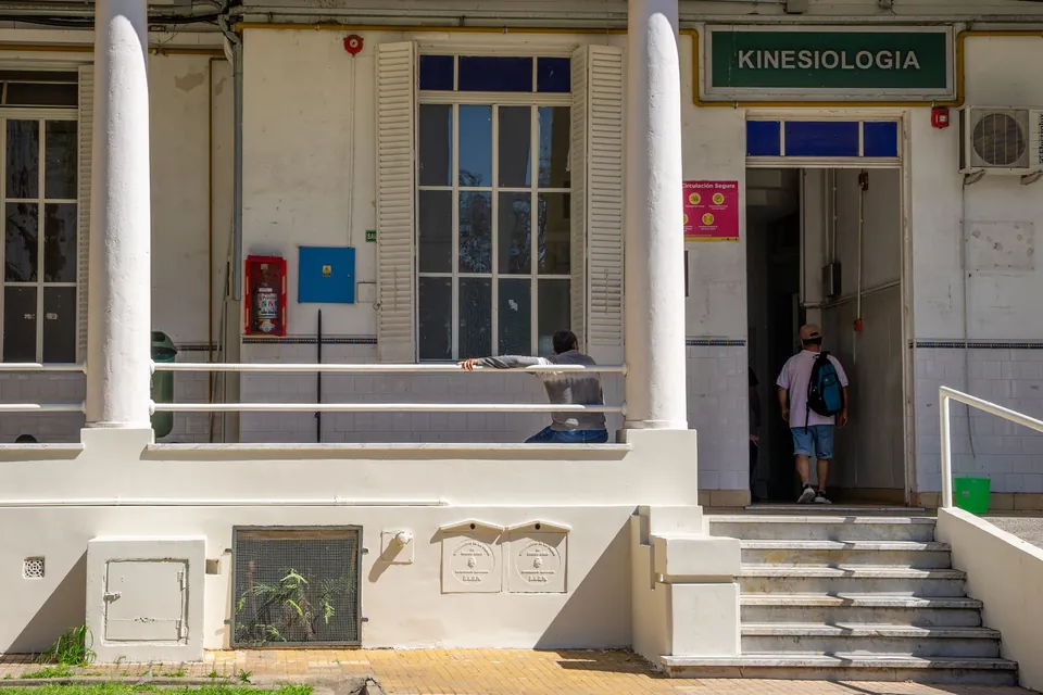 Fachada de un centro de salud con columnas blancas y el letrero de Kinesiología sobre la puerta
