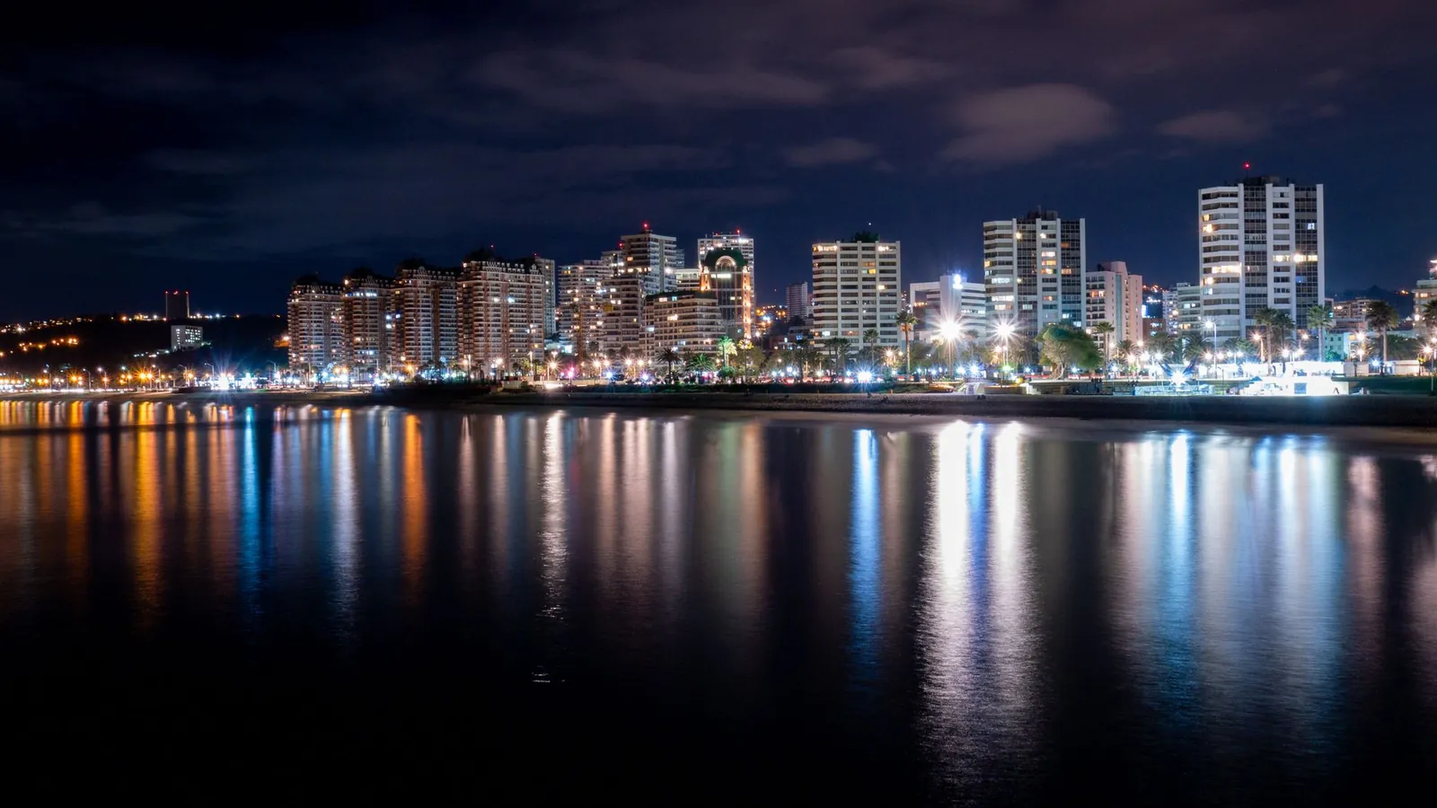 Viña del Mar de noche, con los edificios iluminados reflejados en el mar